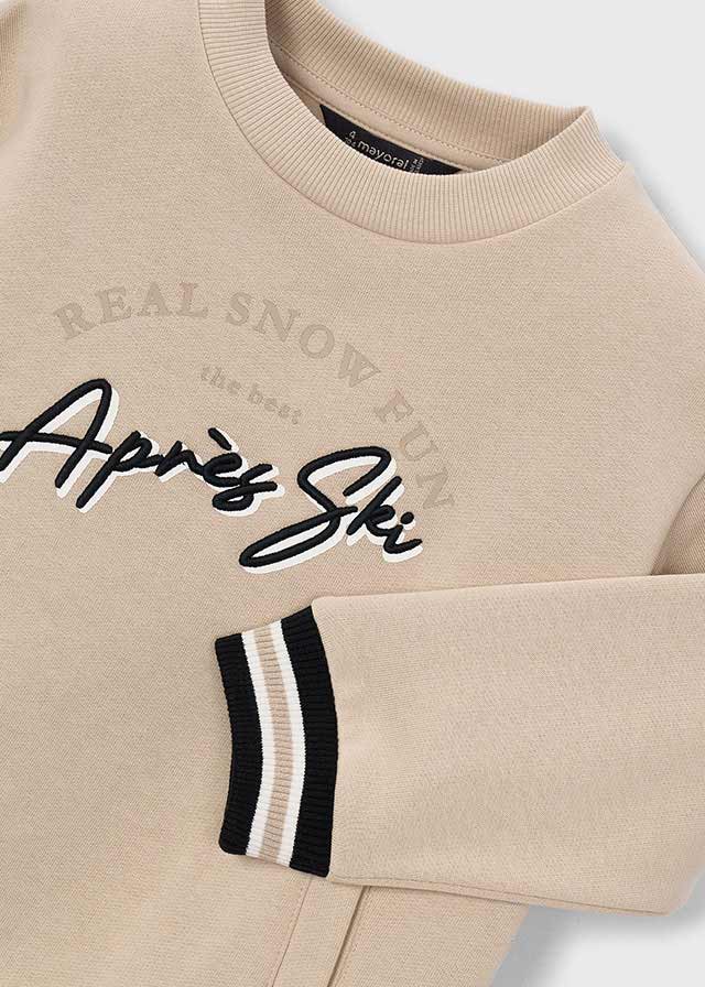 Крупний план бежевого світшота для хлопчика: REAL SNOW FUN the best Après Ski та смугастий манжет