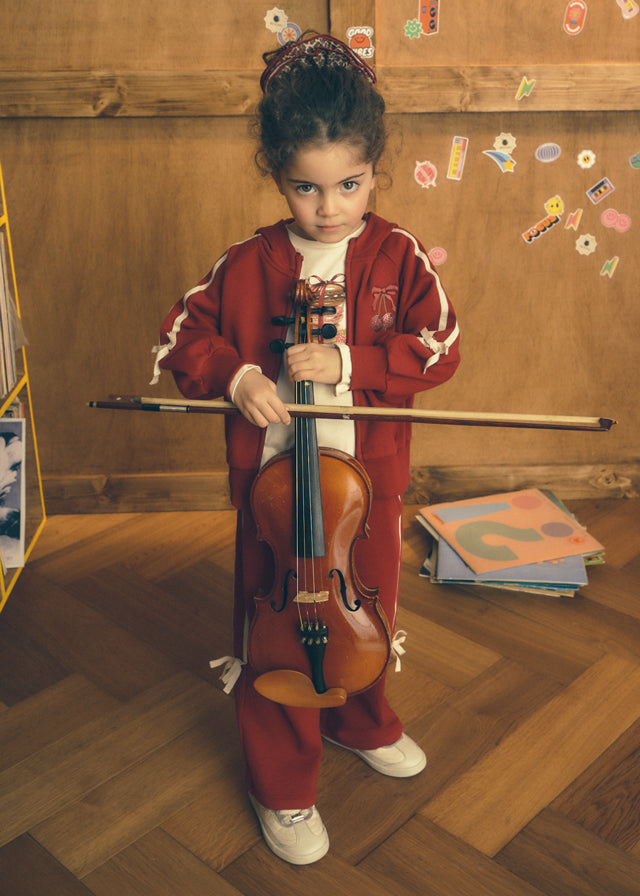 Вишневий спортивний костюм Mayoral з бантами на дівчинці зі скрипкою